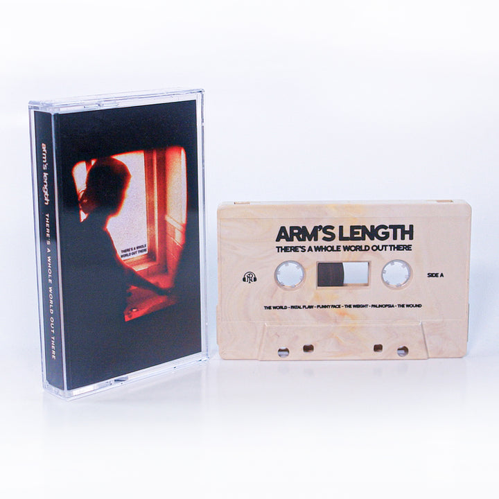 A cassette tape and case from Arms Length are shown. The tape reads THERES A WHOLE WORLD OUT THERE. The cover displays a silhouette at a window with warm orange light, and the track list appears inside.