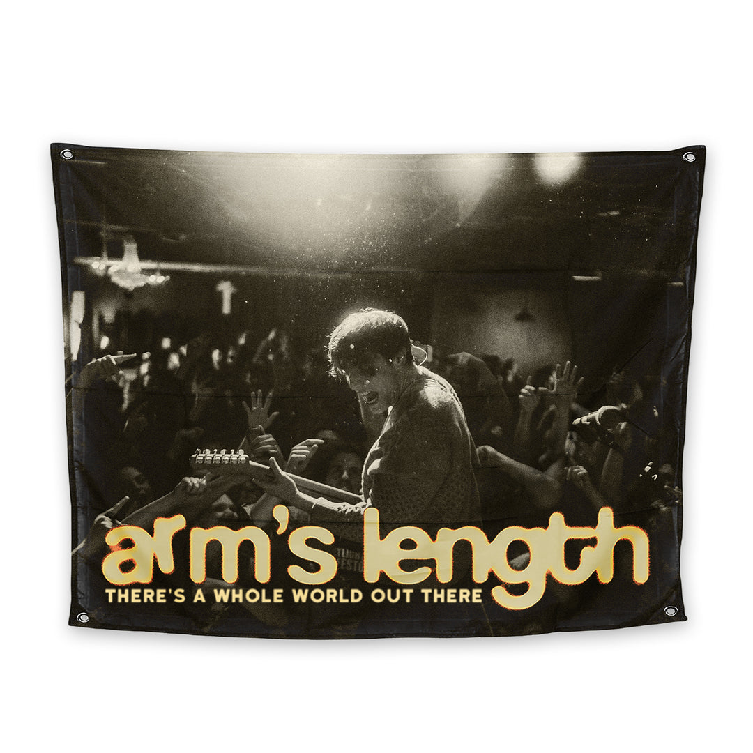 A vibrant 3 x 5 flag featuring a musician on stage and bold yellow and white Arms Length plus THERES A WHOLE WORLD OUT THERE text—now available as an exclusive Arms Length presale item.