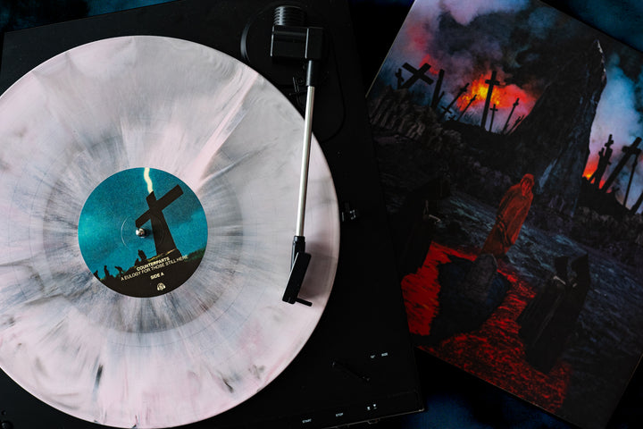A white, gray, and oxblood marbled Counterparts vinyl spins, its label featuring crosses and lightning. The dramatic album cover depicts a dark landscape with black-hooded figures among the crosses.
