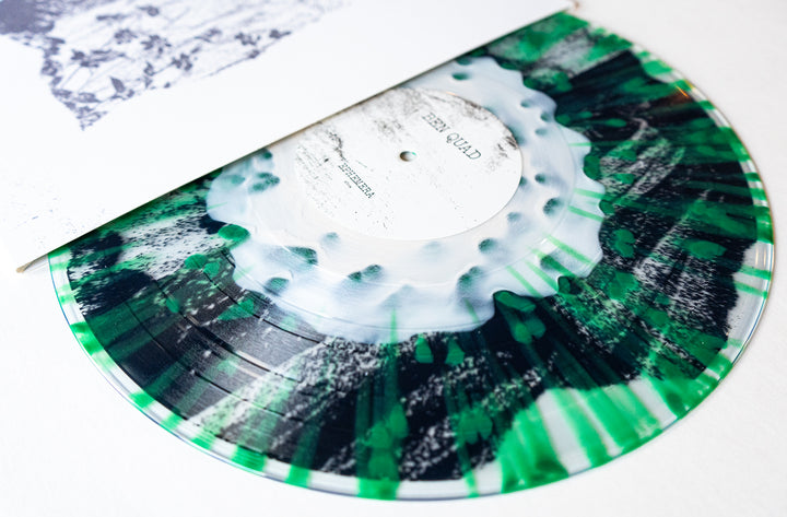 A close-up of a marbled green, black, and white Ben Quad vinyl record, partially pulled from a white album cover with black and white artwork—ideal for collectors looking for pressing details.