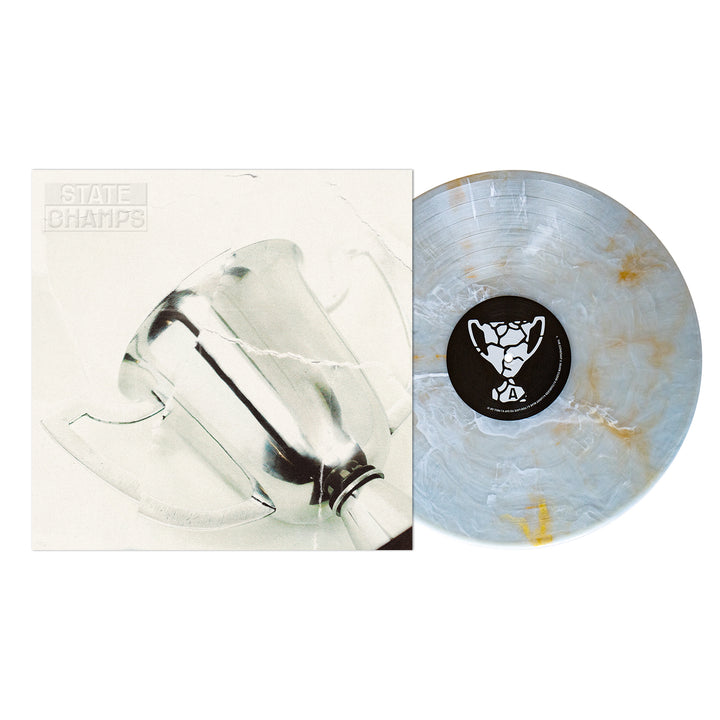 A State Champs vinyl record with a Golden Pearl Deluxe Marble Blend pattern is displayed beside its album cover, which shows a silver trophy tilted on a white background. The band name appears faintly in the top left corner.