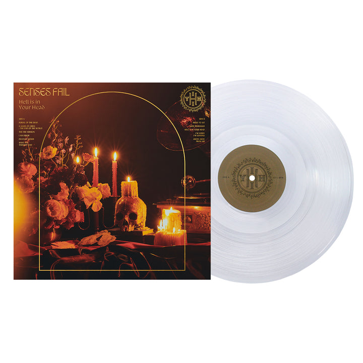 A transparent vinyl record by Senses Fail sits next to its album cover, showing lit candles, flowers, and a mirror on a dark table bathed in warm golden light. The album is Hell is in Your Head, exploring themes like The Burial of The Dead.