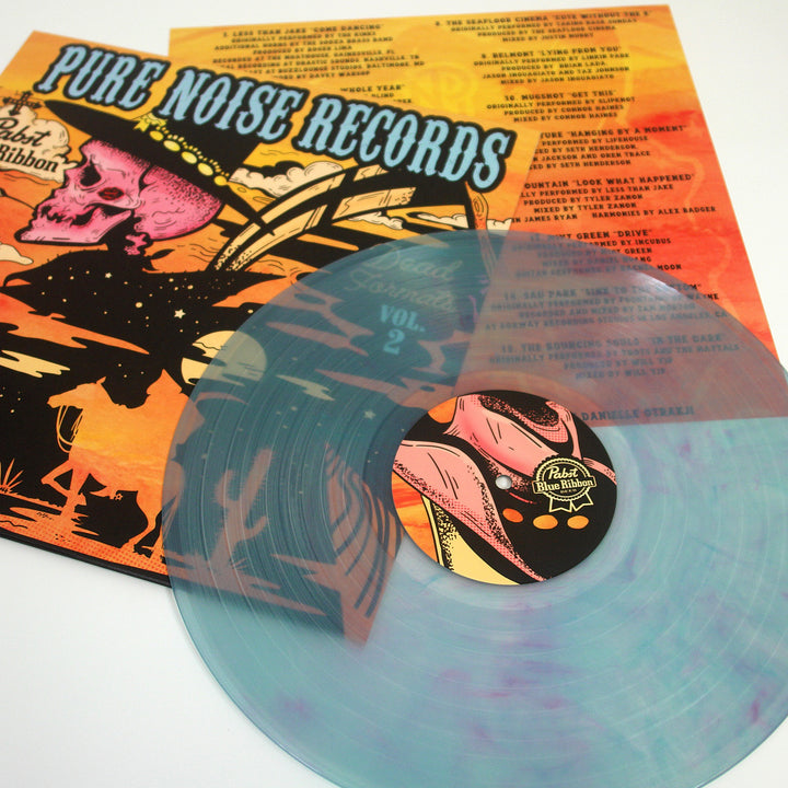 A translucent blue Dead Formats vinyl rests on an illustrated album cover with a pink skull. The orange track list appears in the background, highlighting the iconic release from Dead Formats.