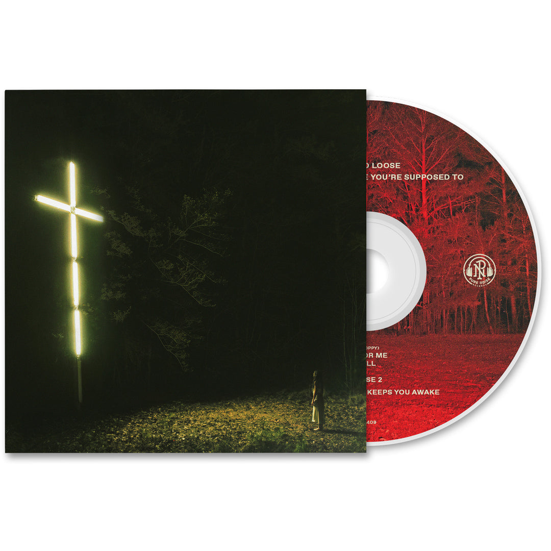 A CD from Knocked Loose slides partially from its case, revealing a glowing cross-shaped light in a dark forest on the cover. The red disc features black detailing and text. Pre-order now to secure your copy before the album releases!.