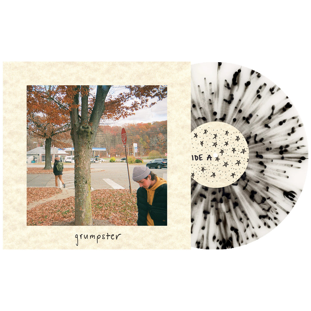A Grumpster vinyl in Milky Clear with Heavy Black Splatter rests next to its album cover, showing two people outdoors in autumn by a tree and crosswalk. Grumpster appears at the bottom—ideal for any LP presale collection. Brand: Grumpster.