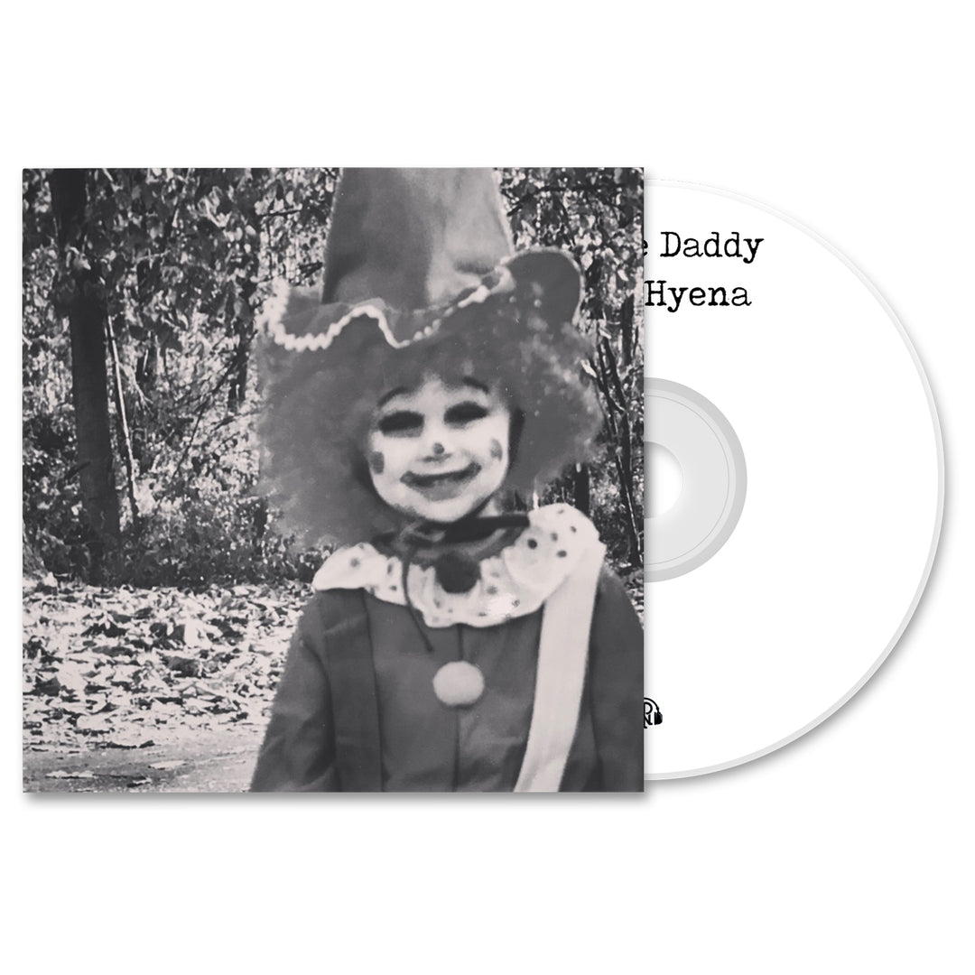 Black-and-white photo of a child clown—pointed hat, curly wig—smiling outdoors among autumn leaves; next to the image is a Prince Daddy & The Hyena CD, suggesting an album release.