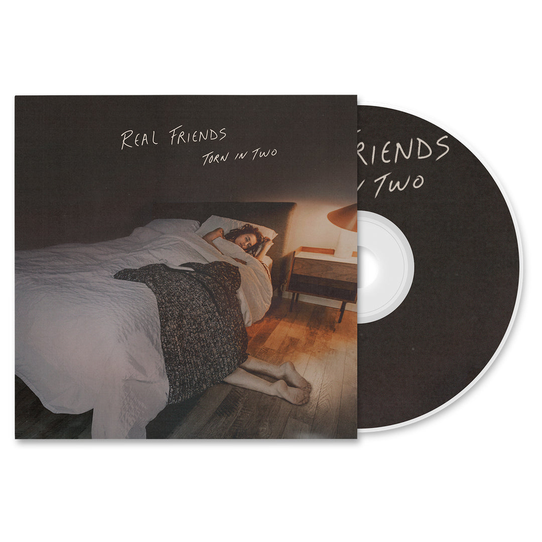 Album cover and CD for Torn in Two by Real Friends. The CD shows a person lying under a blanket in a dim room with wooden floors and a nightstand lamp.