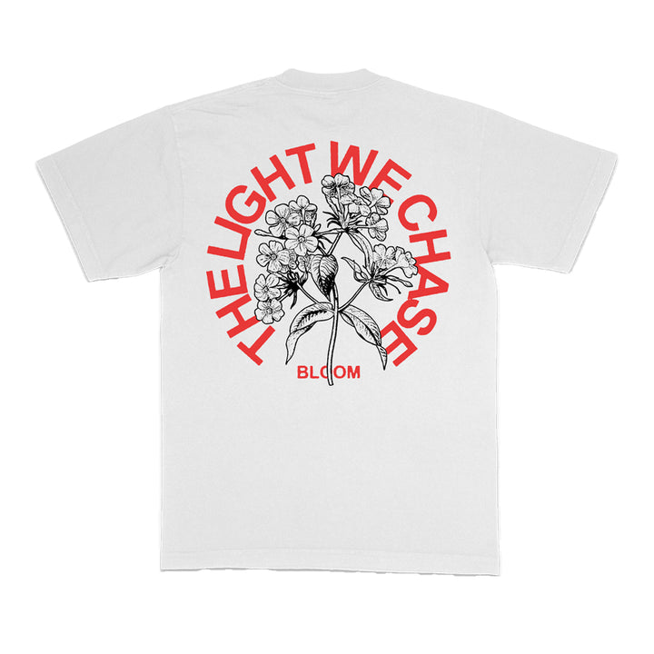 The Bloom white T-shirt showcases a bold black floral illustration on the back, with red arched text reading THE LIGHT WE CHASE and BLOOM printed in red below the design.
