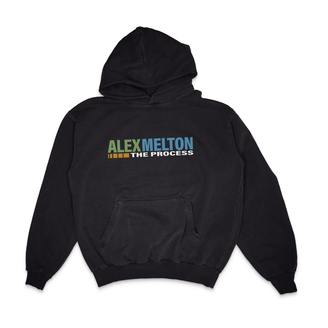 A black Alex Melton hoodie with a front pocket and colorful block letter text "ALEX MELTON THE PROCESS" printed on the chest.