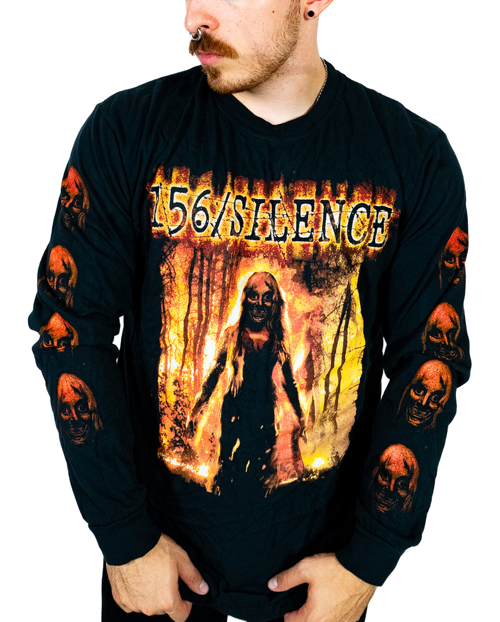 A person wearing a black Comfort Colors long sleeve shirt with 156/SILENCE and a horror-themed graphic of a figure in flames. Made from soft ring spun cotton and garment dyed for lasting quality, the sleeves feature multiple red skulls. The person is looking to the side.