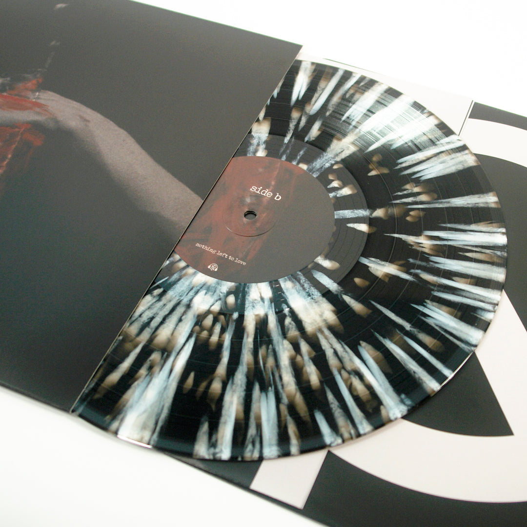 A marbled black and white vinyl from Counterparts, part of a limited edition 6th Press of only 2000, is partly pulled from its sleeve to reveal the side B label and an abstract streaked design on the disc.
