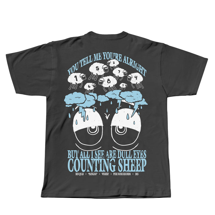 Ben Quad black T-shirt with a Sheep Pepper graphic: tired eyes below, clouds, and numbered sheep jumping above. Features the text: You tell me you’re alright but all I see are dull eyes counting sheep.
