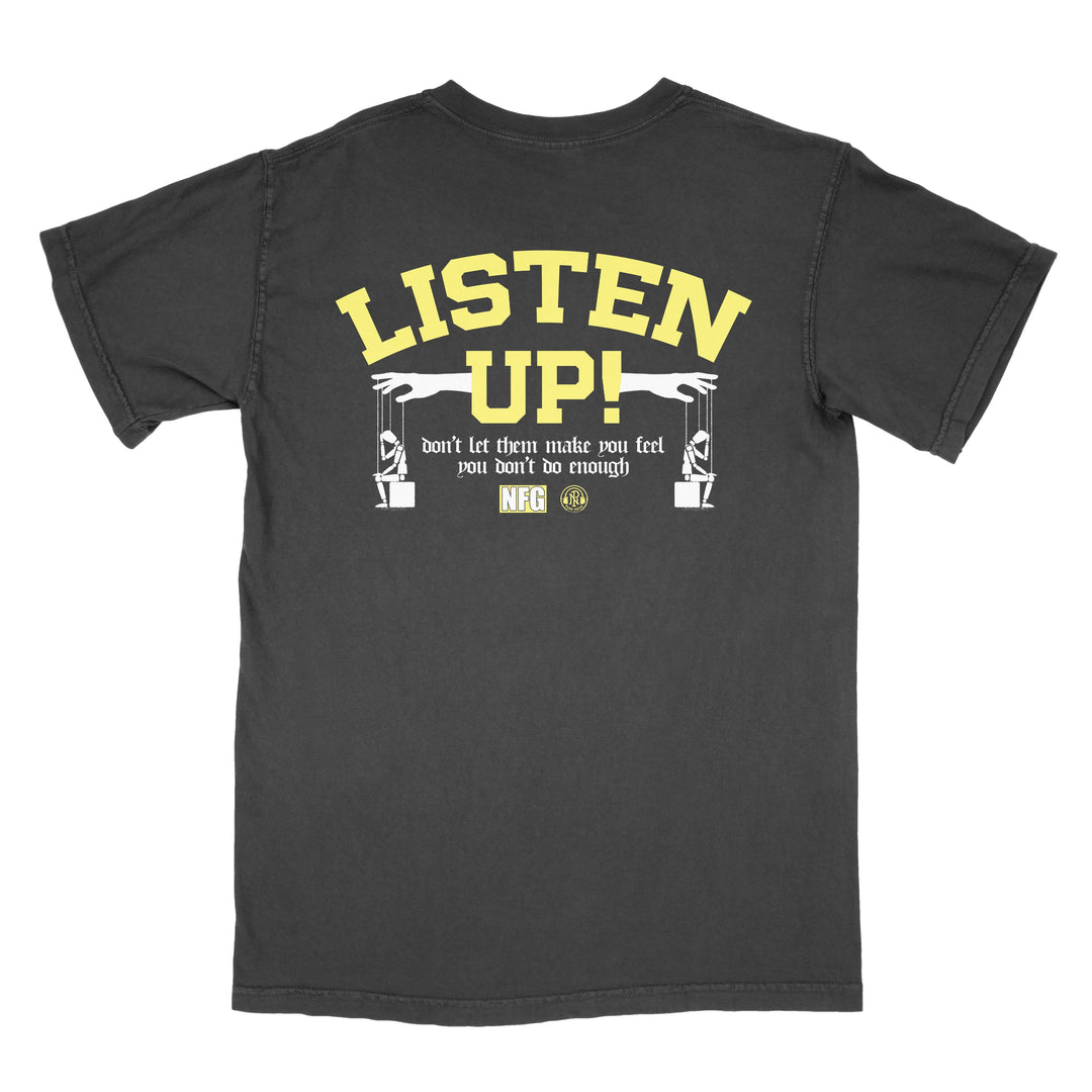 A black New Found Glory tee with bold yellow "Listen Up!" text on the back, smaller text "don’t let them make you feel you don’t do enough," and two illustrated arms holding wireless audio microphones below.