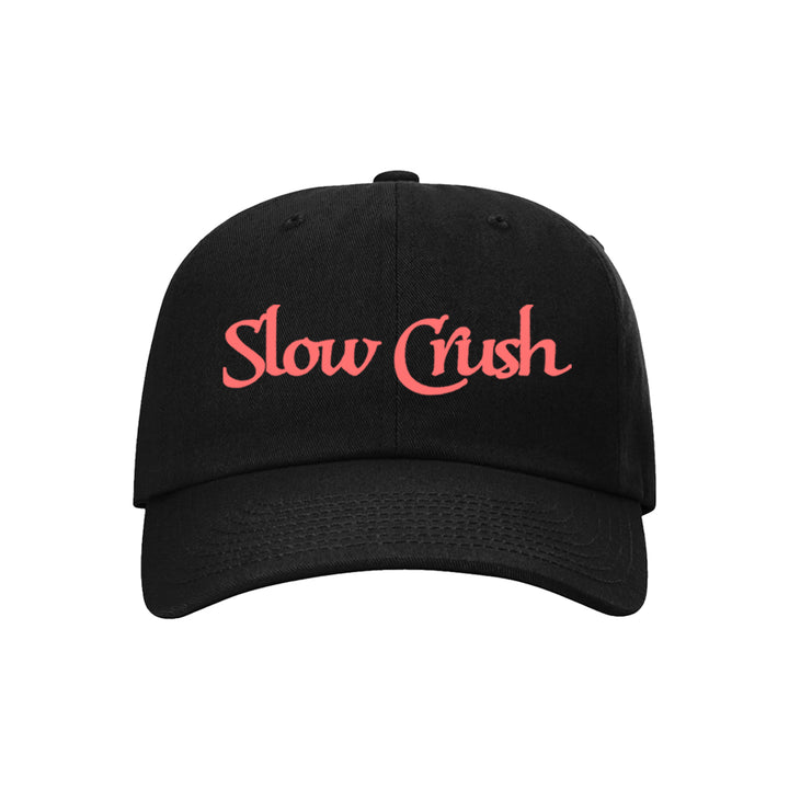 The Slow Crush black dad hat features the brand name in pink stylized letters on the front, offering laid-back style to any outfit.