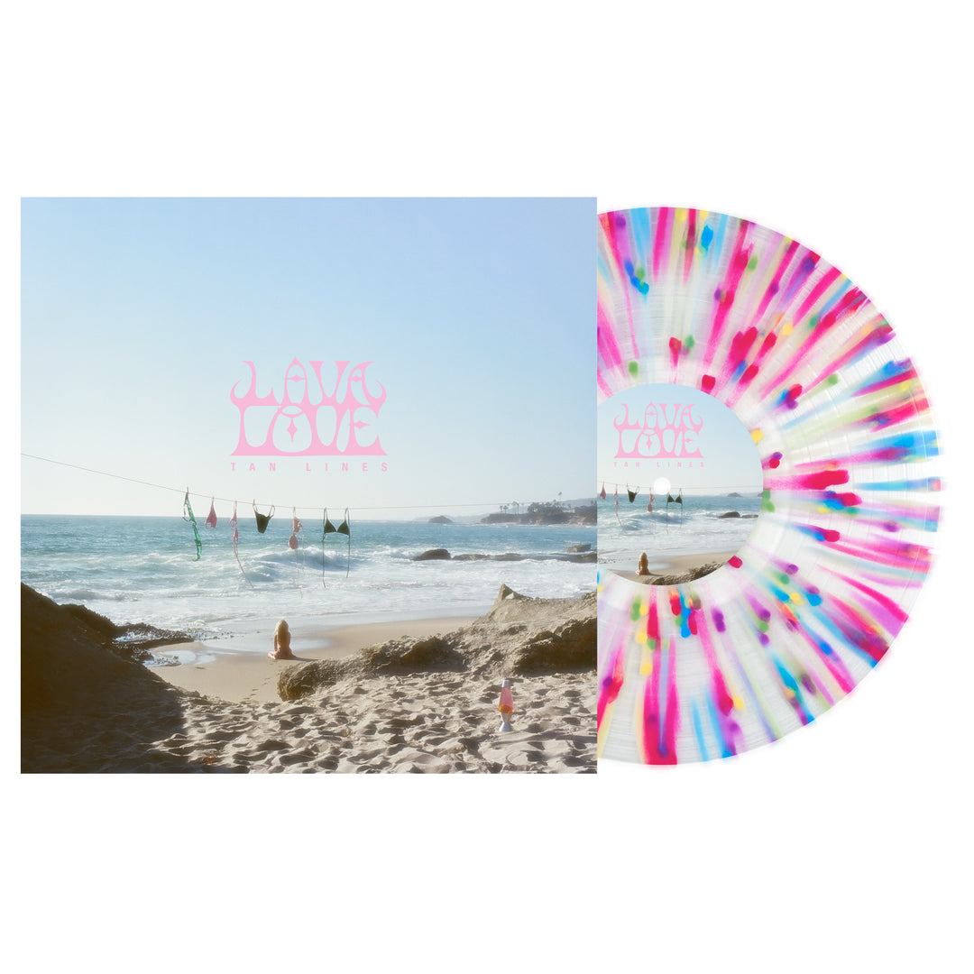 A LAVALOVE Rainbow Splatter LP in pink, blue, and white rests next to its album cover, which shows a beach scene with bikinis on a clothesline and “Lava Love Tan Lines” written in pink.