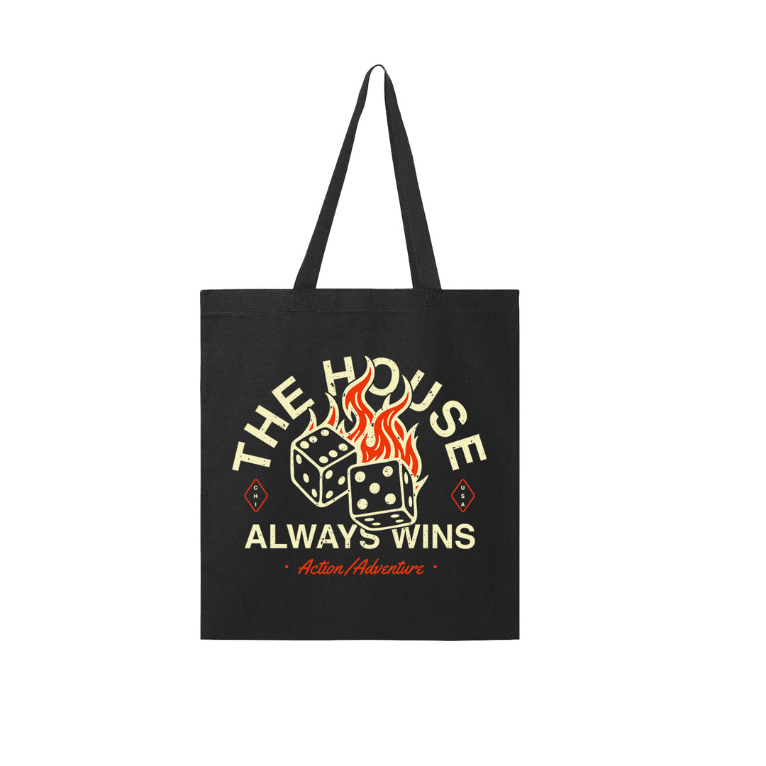 Black tote bag by Action/Adventure featuring two flaming dice and the phrases THE HOUSE ALWAYS WINS and Action/Adventure in bold, stylized fonts—perfect for casino lovers.