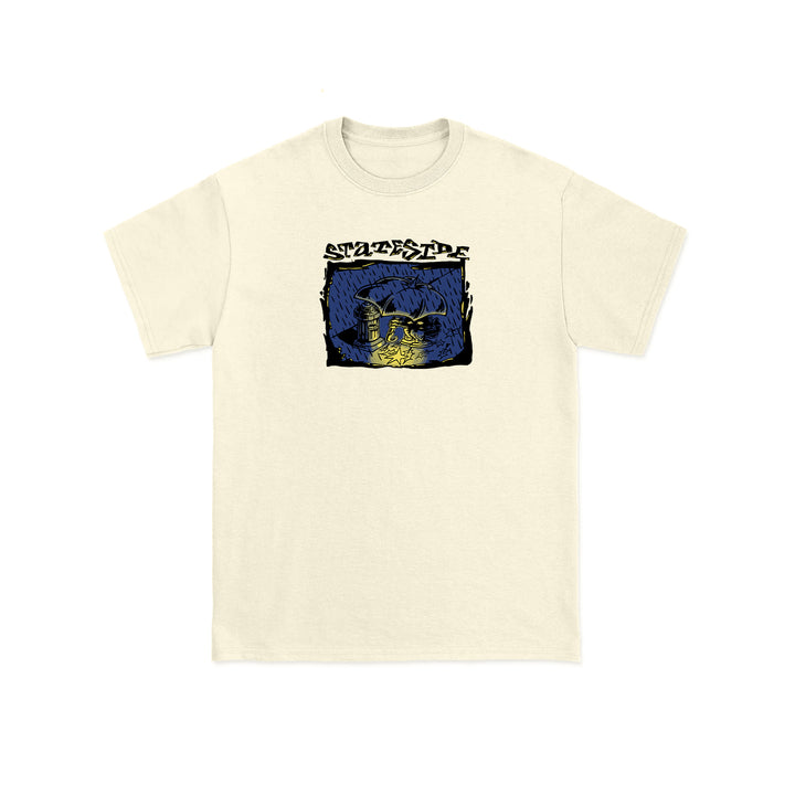 Beige Stateside t-shirt featuring a chest graphic with a blue and yellow shark and underwater scene. STATESIDE appears above the illustration in bold, stylized lettering.