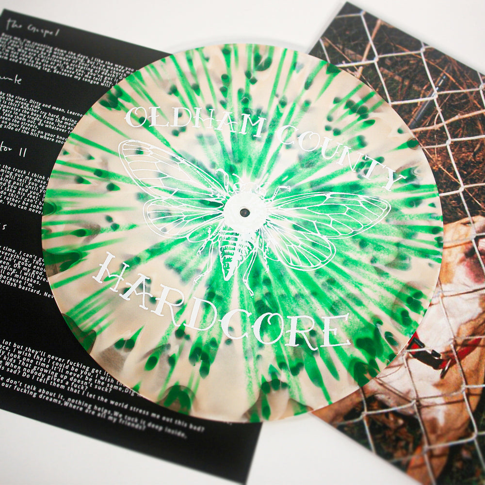 This limited edition Knocked Loose vinyl features a green and white splatter design, a large insect illustration, and "OLDHAM COUNTY HARDCORE" text, and comes with a lyric/photo booklet—ideal for collectors.