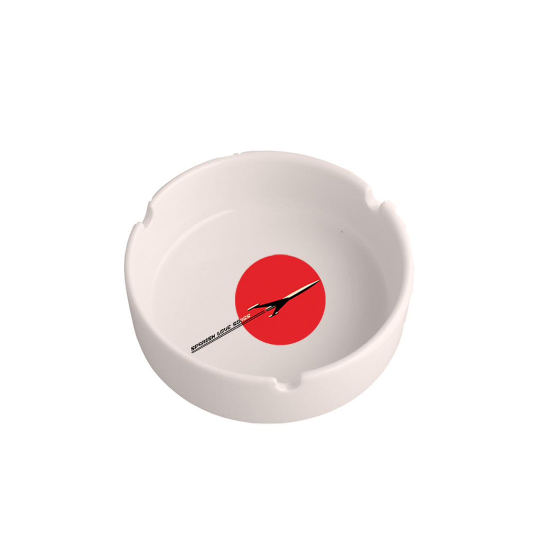 A white ashtray by Spanish Love Songs featuring a red circle and a black airplane graphic, reminiscent of the Japanese flag—perfect for collectors seeking a unique Rocket Ashtray.