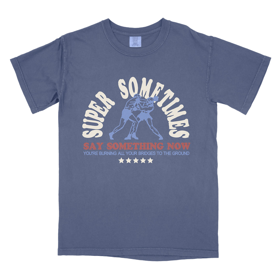 Navy blue t-shirt by Super Sometimes featuring two boxers, “SUPER SOMETIMES” above, and “SAY SOMETHING NOW YOU’RE BURNING ALL YOUR BRIDGES TO THE GROUND” with five stars below the graphic.