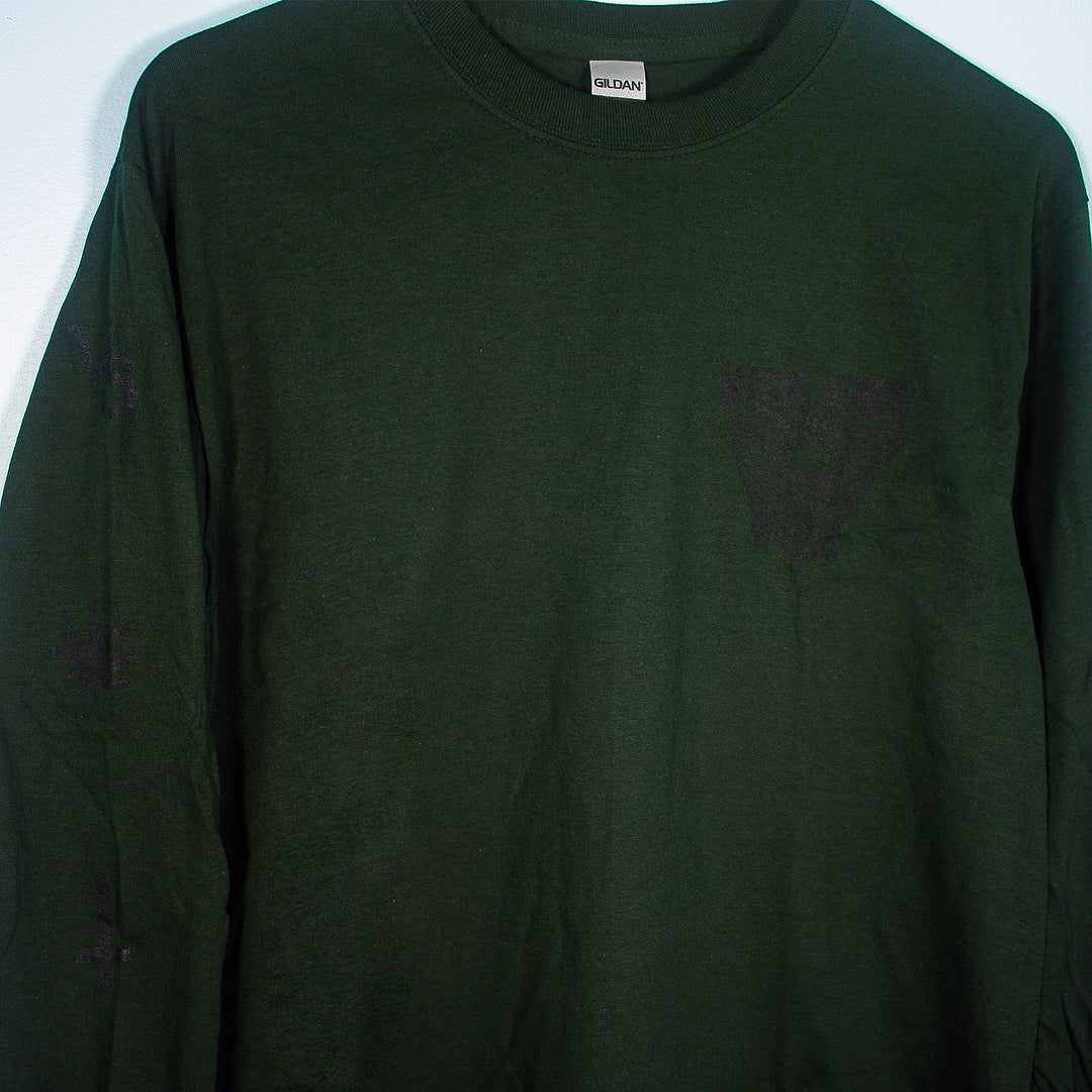 A forest green Violent Soho long sleeve shirt hangs against a light wall. Faint black print appears on the left chest and sleeve, but the text and design are hard to read.
