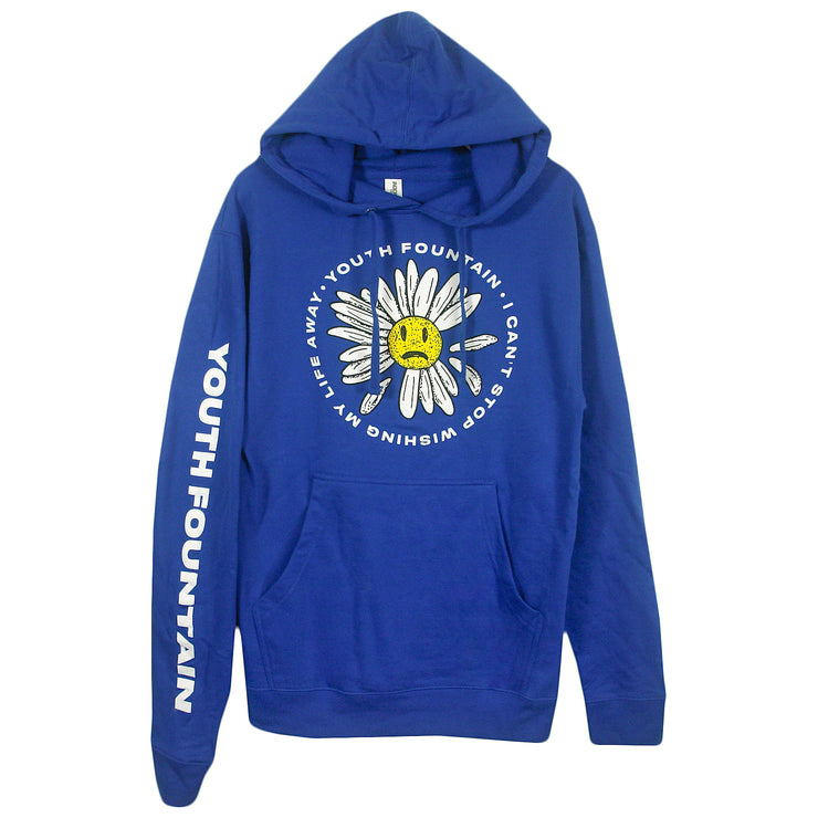 image of a royal blue pullover hoodie on a white background. hoodie has front center print of a daisy with a sad face in the center. around it says youth fountain i can't stop wishing my life away. the left sleeve has a print that says youth fountain