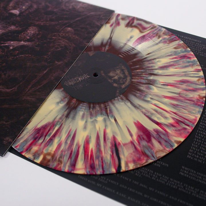 A close-up of a Vomit Forth vinyl record from the In the Name of the Father album, featuring a cream base with red and brown splatter pattern, partially out of its sleeve and resting on a printed sheet with white text.