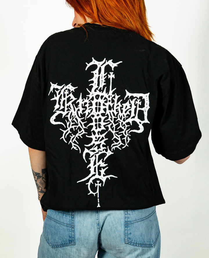 Person with long red hair wears a black Knocked Loose T-shirt made from premium USA cotton, featuring an intricate white design on the back. Paired with light blue jeans, the person is turned away to highlight the graphic on this garment dyed tee.