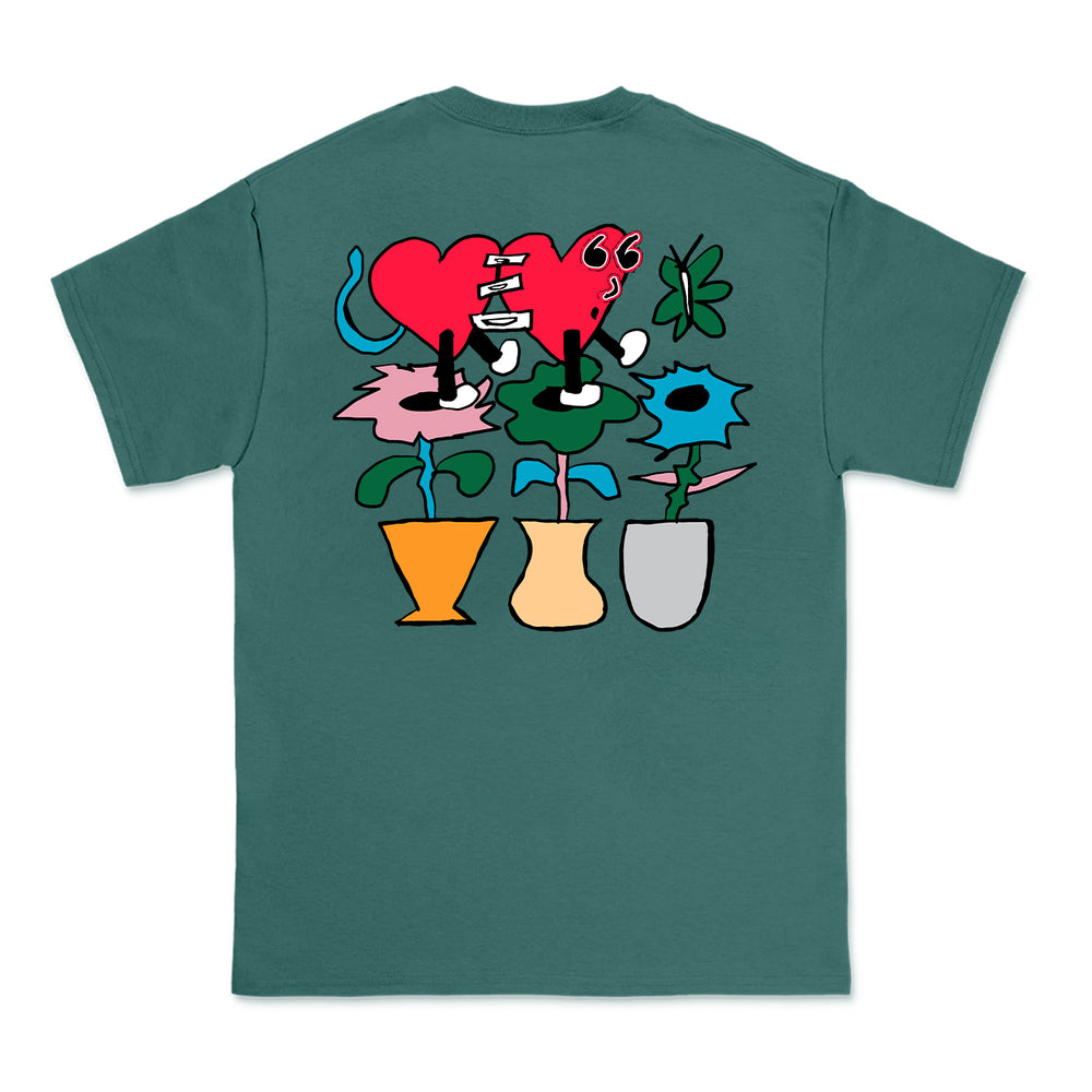 Knuckle Puck Teal Comfort Colors T-shirt with a large cartoon graphic on the back: a stitched red heart with two eyes and three abstract flowers in orange, beige, and gray vases, all with green stems and leaves.