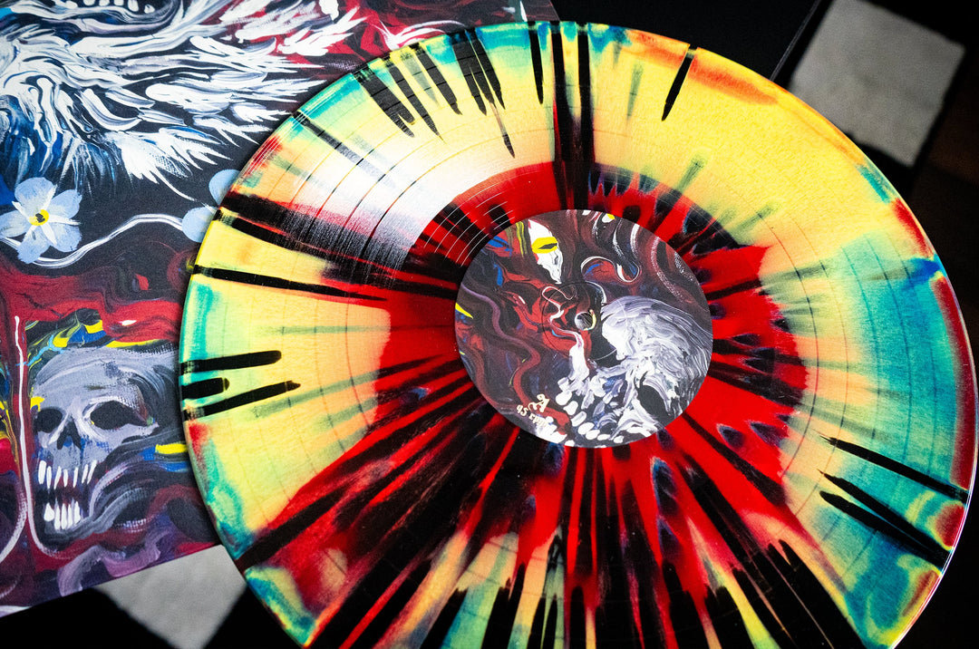 The Mugshot Vinyl LP features a vibrant yellow, red, green, and heavy black splatter design with a central skull illustration. Partially covering an equally vivid album cover with matching skull art. Available now for presale.