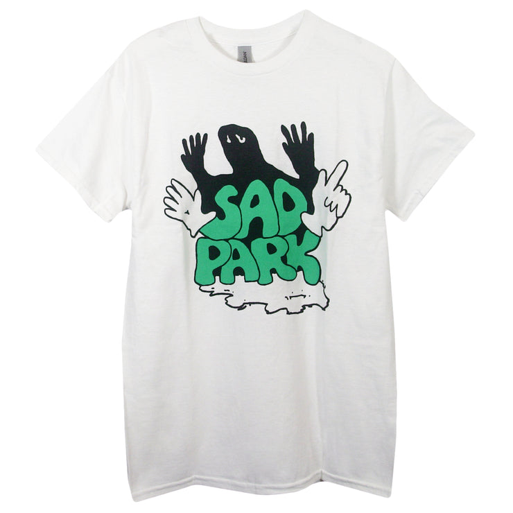 image of a white tee shirt on a white background. tee has center print in green that says sad park. behind the text is a black shadow of a person with a face mask and their hands up