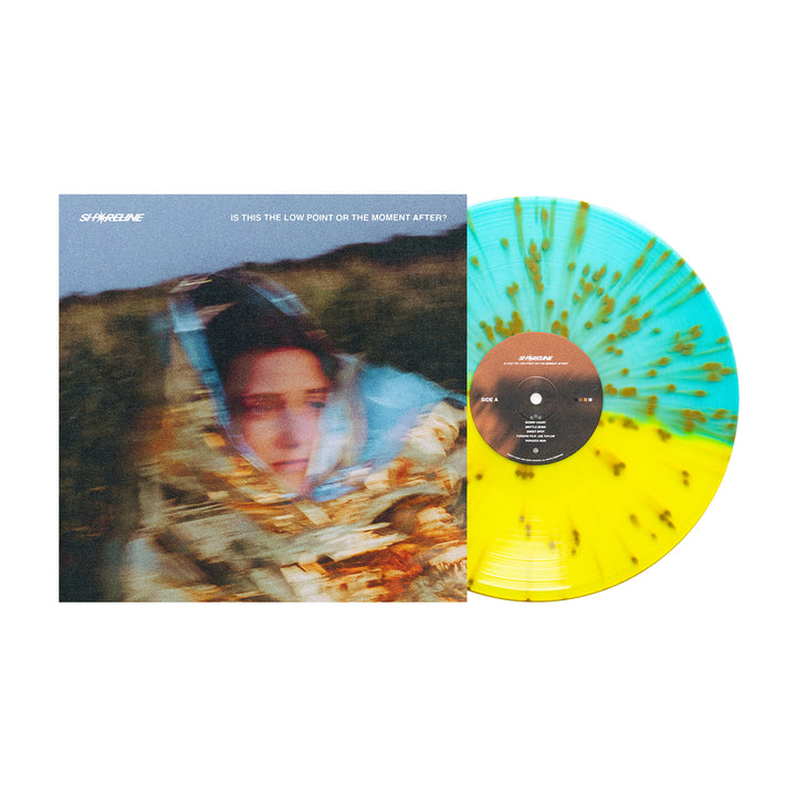 A Shoreline Gold Splatter Vinyl LP sits beside its album cover, showing a blurred figure in a foil blanket. The title on the cover reads “IS THIS THE LOW POINT OR THE MOMENT AFTER?”.