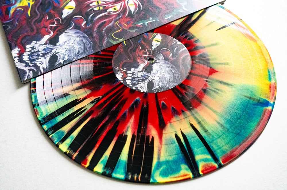 A vibrant Mugshot red vinyl record with red, neon yellow, black, and green splatters is partially slid out from an illustrated cover with swirling shapes and bright eyes. Album release date: June 2025.