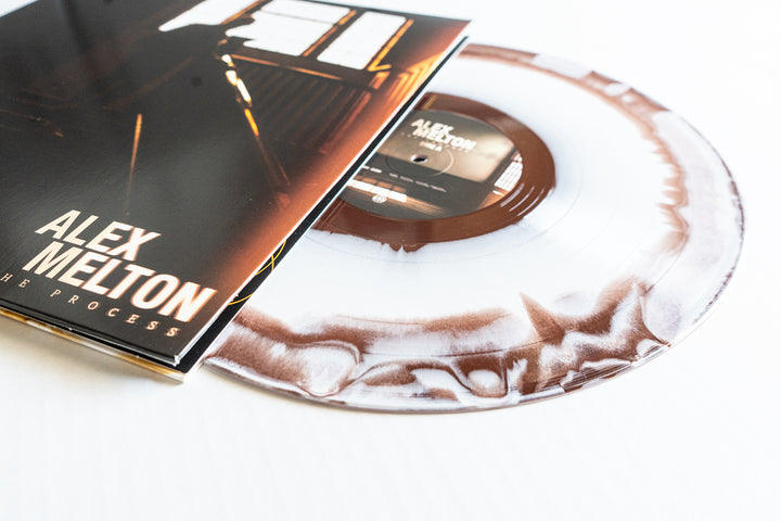 A white and brown marbled vinyl LP by Alex Melton, featuring a sleeve with "THE PROCESS" album title and a warmly lit piano image, is now available for presale.