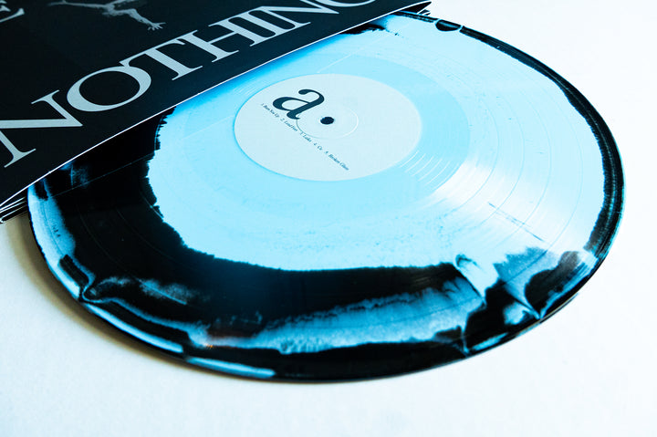 A black and blue splatter vinyl record partially slides out from its cover, which features the word NOTHING in bold white letters—an eye-catching vinyl pressing from Boston Manor that celebrates the 10-year anniversary of their album "Be Nothing.