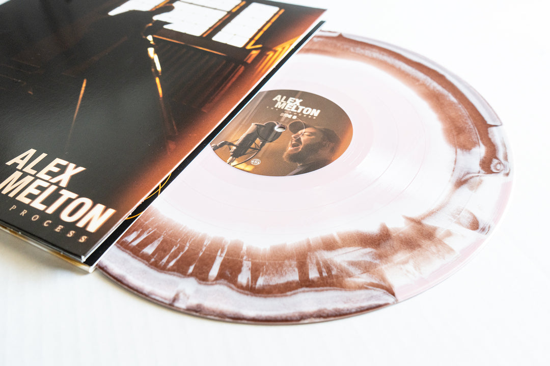 A brown and white marbled vinyl LP partially out of its sleeve, featuring Alex Melton’s name and a portrait of a man singing into a microphone, from The Process album presale.