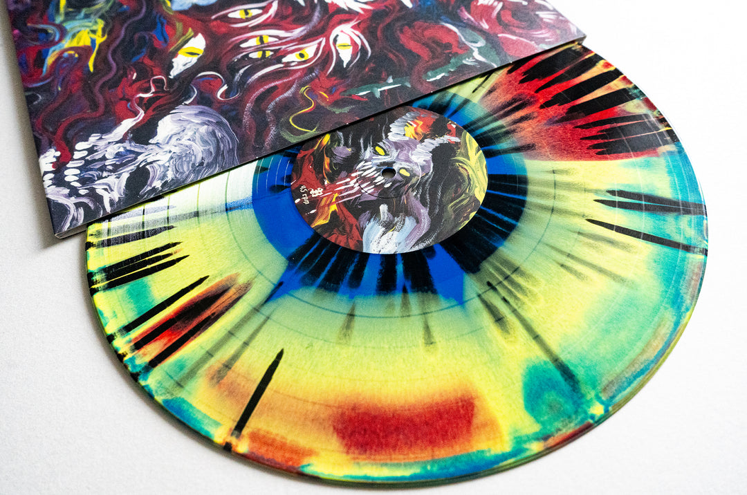 A vibrant red vinyl by Mugshot with neon yellow, green, and blue splatters is partially removed from its surreal album cover featuring multi-eyed, abstract artwork. Album release date: June 2025.
