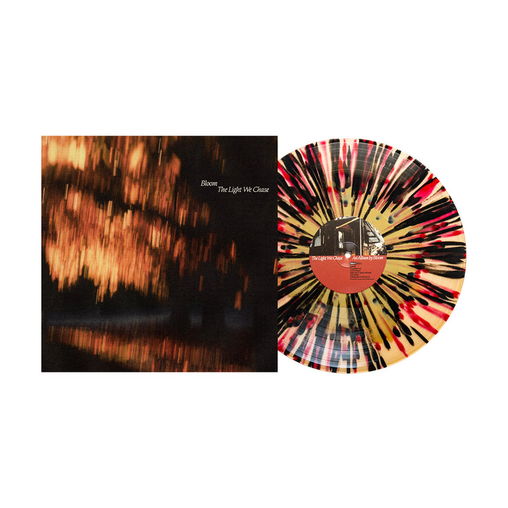 A The Light We Chase vinyl by Bloom, featuring a cream base with black, red, and brown splatters, sits beside its album cover of blurred warm lights on water. This stunning presale edition is perfect for collectors.