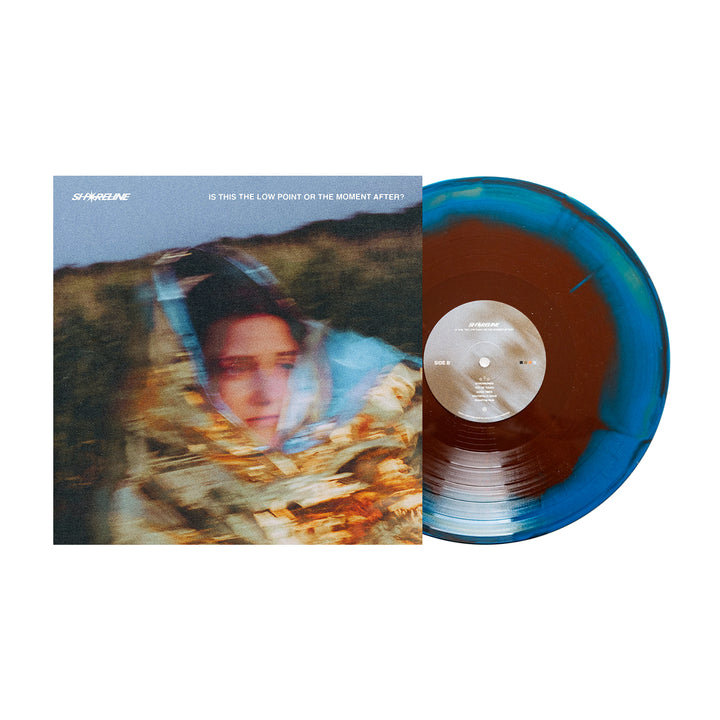 A limited edition Gold/Blue/Brown Vinyl LP by Shoreline sits next to its cover, featuring a blurred person wrapped in a metallic blanket outdoors. The album is titled Is This the Low Point or the Moment After?.