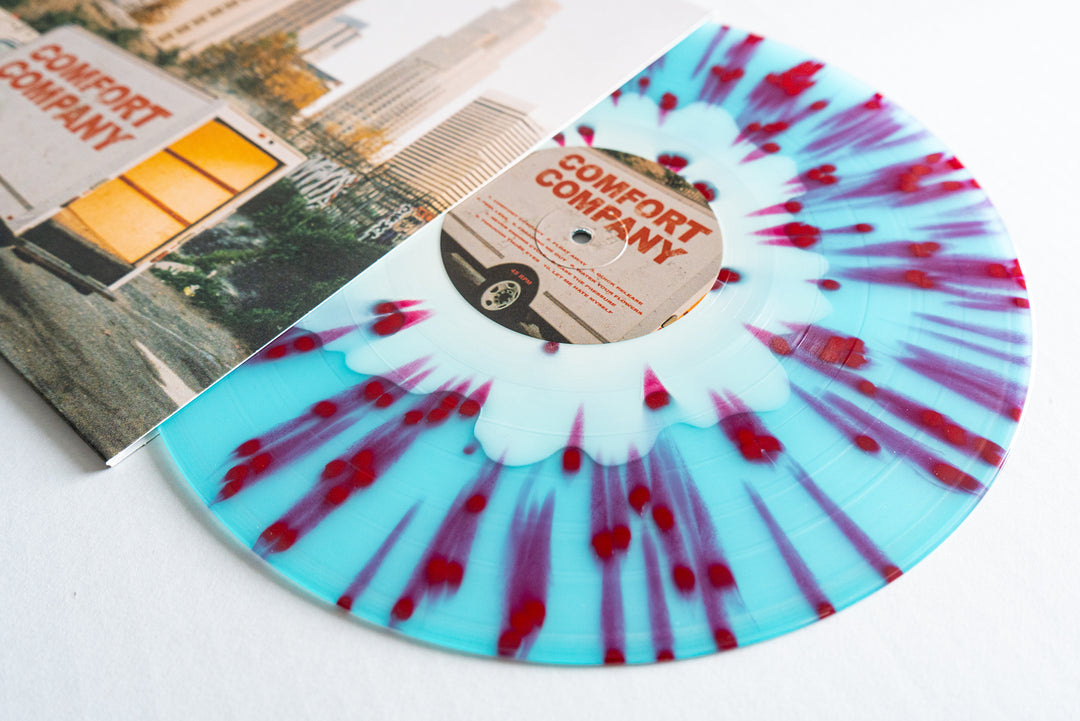 A blue Bearings "Electric Blue Vinyl" record with red and white splatters is partially pulled from an album cover featuring a truck and the text Comfort Company, which also appears on the record label.