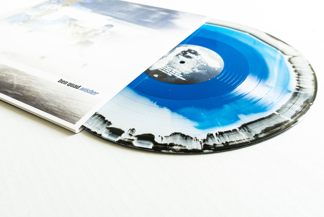 A blue and black marbled Wisher Blue Vinyl LP by Ben Quad partially slides out of its minimal, faded cover featuring indistinct images and "Denovali" in small print. Album presale available now.