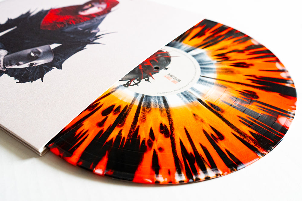 A vibrant black and orange splatter vinyl by The Amity Affliction, partially shown in its abstract, dark-themed cover with two faces—an Amity Exclusive collector’s item.