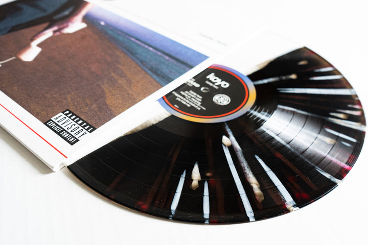 A KOYO vinyl LP partially pulled from its album cover reveals a unique Barely Here vinyl design, a parental advisory explicit content label, and cover art featuring a beach scene.