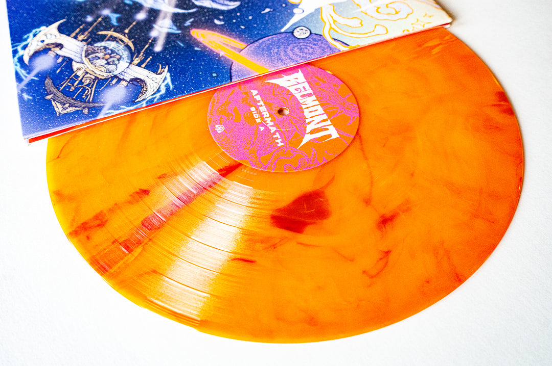 A 2nd Press Limited Edition Belmont Sunspot Marble orange vinyl record, partially out of its cosmic and abstract colorful sleeve, displayed on a white surface.
