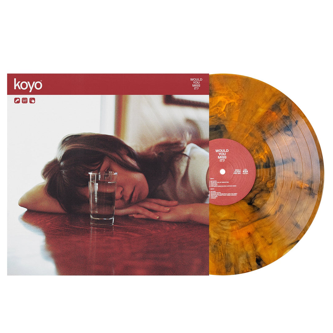 A KOYO vinyl record with a Koi Pond Marble orange and black pattern is partially out of its cover, which features a person resting their head on a table near a glass of water. A red band at the top reads KOYO.