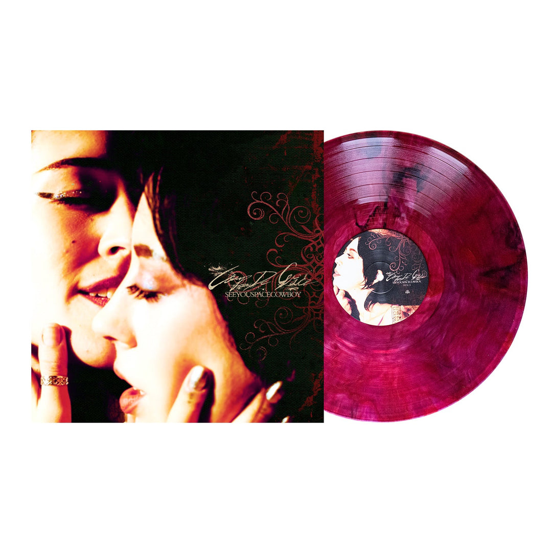 A marbled pink and purple vinyl by SeeYouSpaceCowboy is shown beside its cover, depicting two women touching faces with closed eyes. Ornate script and swirls suggest the album may be Lubricant Like Kerosene.
