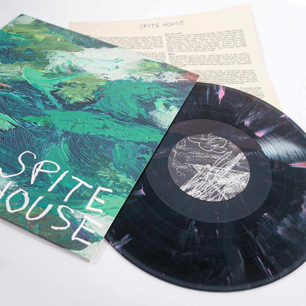 A marbled black, white, and pink vinyl record by Spite House lies beside its cover, which displays a textured abstract green painting with handwritten “Spite House.” Album releases September 12th, 2025.