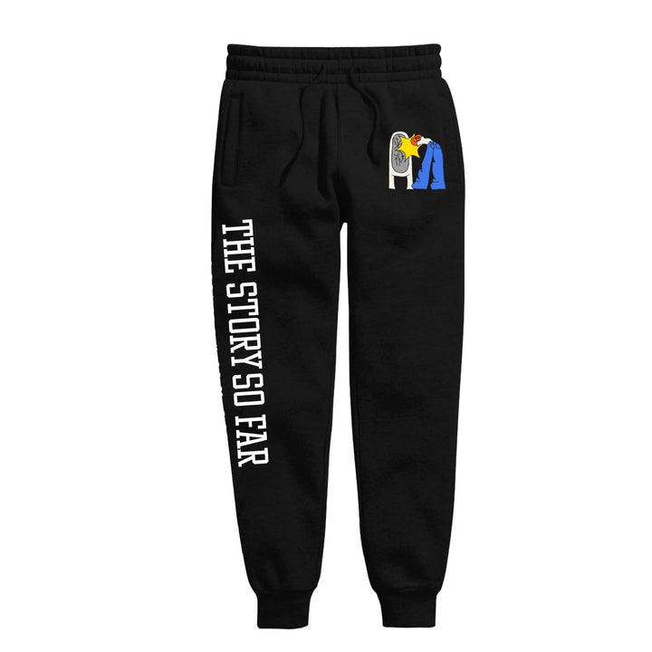 Black sweatpants by The Story So Far with their name printed vertically in white on the left leg and a small graphic of a person leaning into a fan near the right pocket.