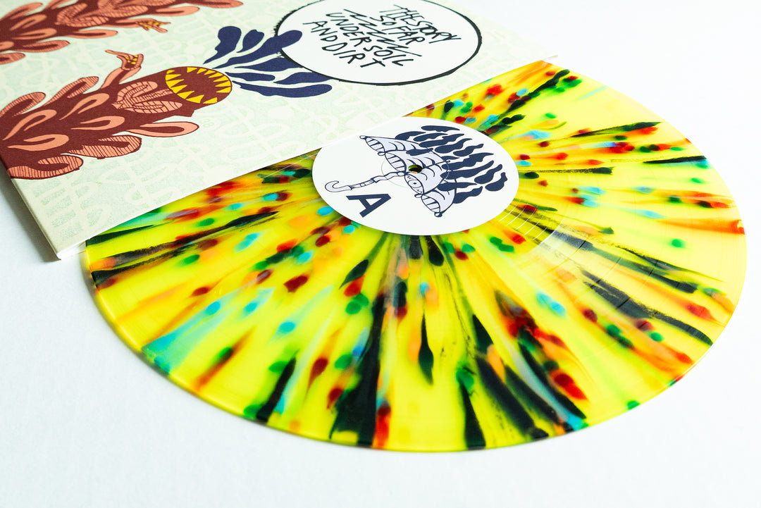 A limited edition yellow vinyl with red, green, and black rainbow splatter by The Story So Far sits partly outside its abstract illustrated cover. Side A is marked by a white label featuring a black umbrella drawing.