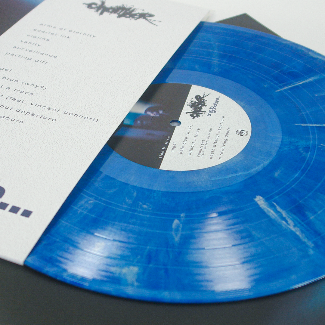 A metallic blue marble vinyl record partially inserted into a white paper sleeve with tracklist text.